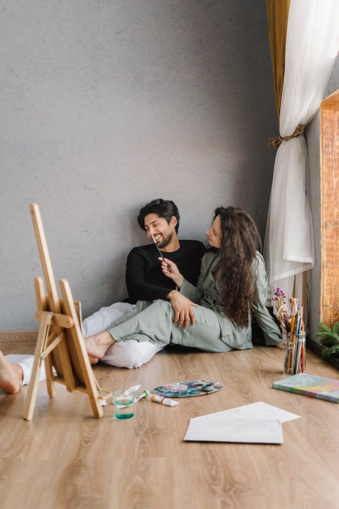 person-couple-art-creative-6933051 A couple smiles while painting together at home, capturing relaxation and creativity.