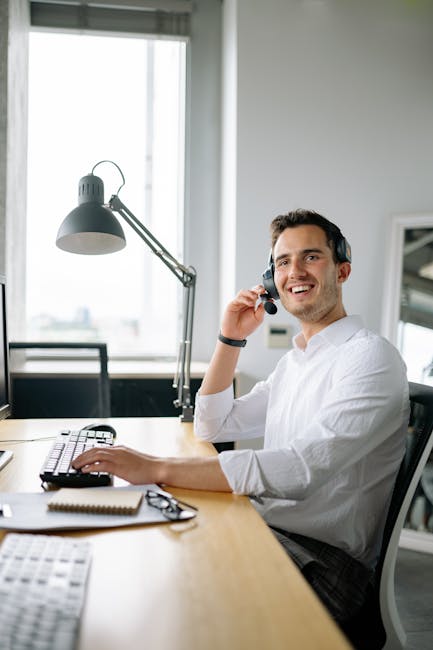 pexels-photo-8867238-8867238 A cheerful call center agent wearing headphones works at a modern office desk.